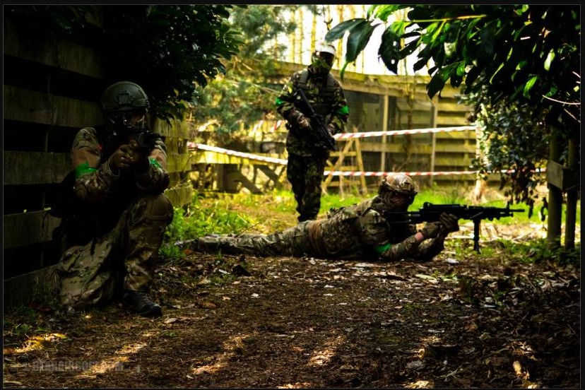 Airsoft players in tactical gear and helmets holding a defensive position during a game