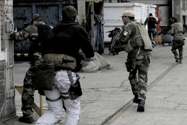 Airsoft players stacked at a corner during a CQB scenario in an urban environment
